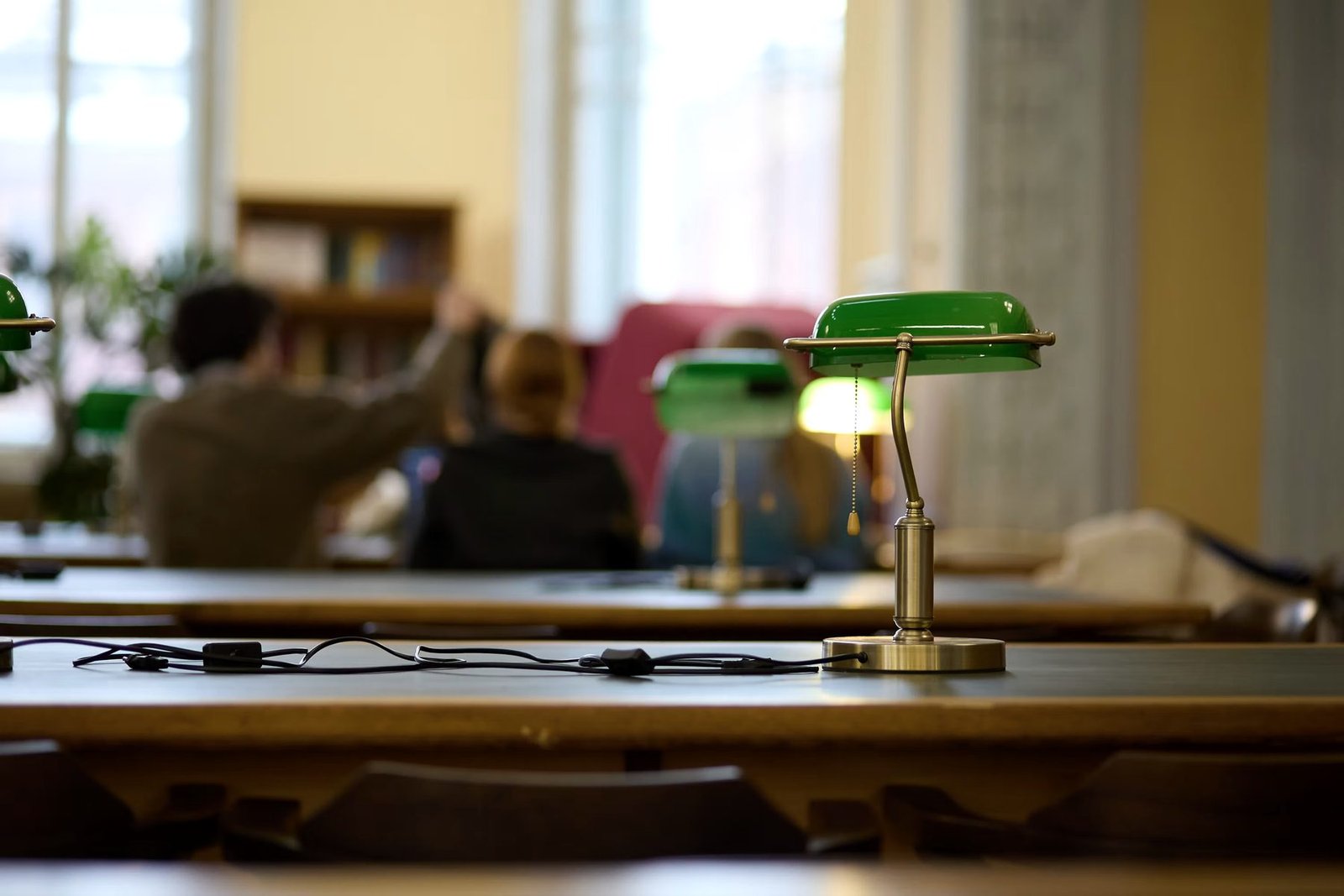 Green-shaded reading lamps on long library tables
